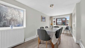 A dining area with a table and chairs, a window with a view, and a radiator.