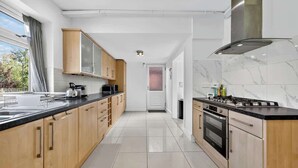A modern kitchen with wooden cabinets, a black countertop, and a stainless steel range hood.