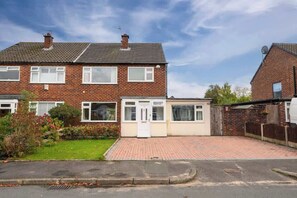 A two-story brick house with a small attached garage, a paved driveway, and a well-maintained lawn.