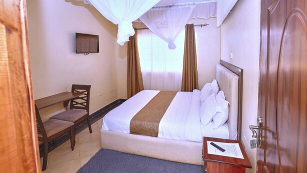 Una habitación de hotel con una cama, un escritorio, una silla, un televisor y una puerta.