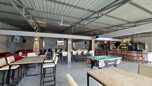 Un amplio espacio interior con varias mesas y sillas, una mesa de billar y una zona de bar.