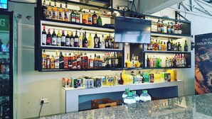 Zona de bar con estantes llenos de botellas de licores y latas de bebidas.