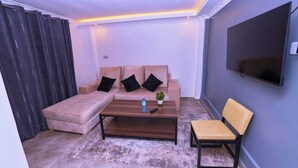 Una sala de estar con un sofá, una mesa de centro y un televisor montado en la pared.