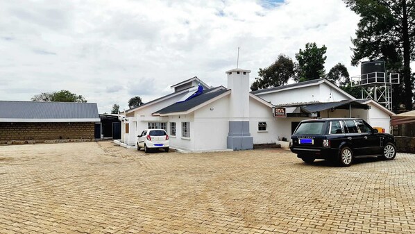 A residential building with a garage, a white car, and a black car parked in front.