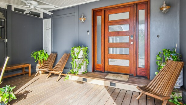 A covered porch with wooden chairs, a bench, and potted plants. - Tropical Lagoon w/ Private Pool & Game Room! (Clearwater)