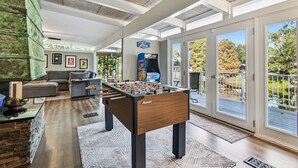 A spacious room with a foosball table, a sofa, and a large window offering a view of the outdoors. - Tropical Lagoon w/ Private Pool & Game Room! (Clearwater)