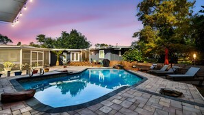 A backyard with a swimming pool, lounge chairs, and potted plants. - Tropical Lagoon w/ Private Pool & Game Room! (Clearwater)