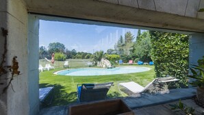 A view of a backyard with a swimming pool, lounge chairs, and a stone feature. - Chambre d'hôtes - B&B - Fleur de Coton (Lagnes)