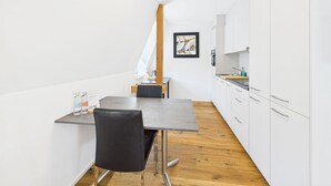 Una cucina moderna con mobili bianchi, un piano di lavoro in legno e una zona pranzo con tavolo e sedie.