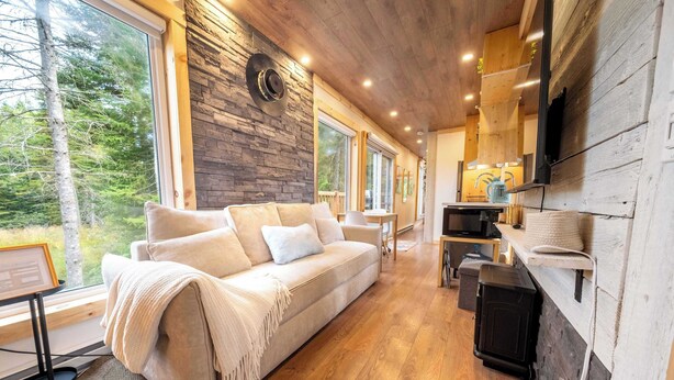 A cozy living room with a sofa, a coffee table, and a TV mounted on a wooden wall.