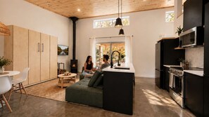 A modern kitchen with a central island, a dining area with a round table and chairs, and a cozy seating area with a sofa. - Saint-Donat | Lux Chalet with spa, sauna & hammam (Notre-Dame-de-la-Merci)