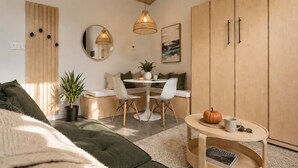 A modern living room with a sofa, a dining table with chairs, a coffee table, and a cabinet.
