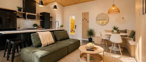 A modern living space with a sofa, coffee table, and a dining area.