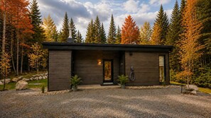 Ett modernt hus med en mörk fasad, en synlig skorsten och en grusuppfart.