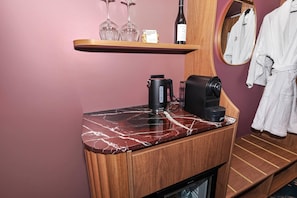 A bathroom with a wooden vanity, a marble countertop, a coffee maker, a bottle of wine, and a robe hanging on a rack. - George Hotel Launceston, An Ascend Collection Hotel (Launceston)