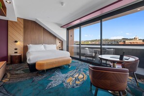 Een hotelkamer met een groot bed, een ronde tafel en uitzicht op de stad.