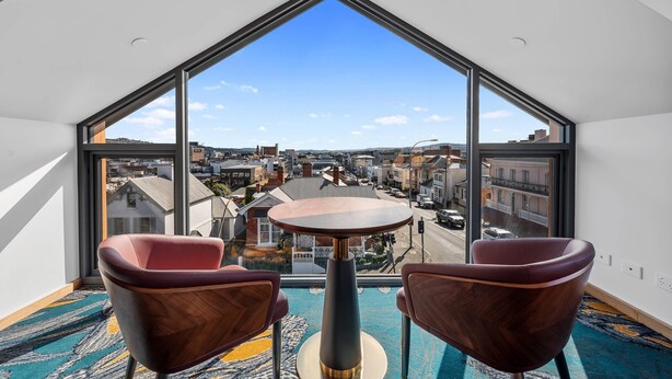 A modern room with a large window, two wooden chairs, and a small table. - George Hotel Launceston, An Ascend Collection Hotel (Launceston)