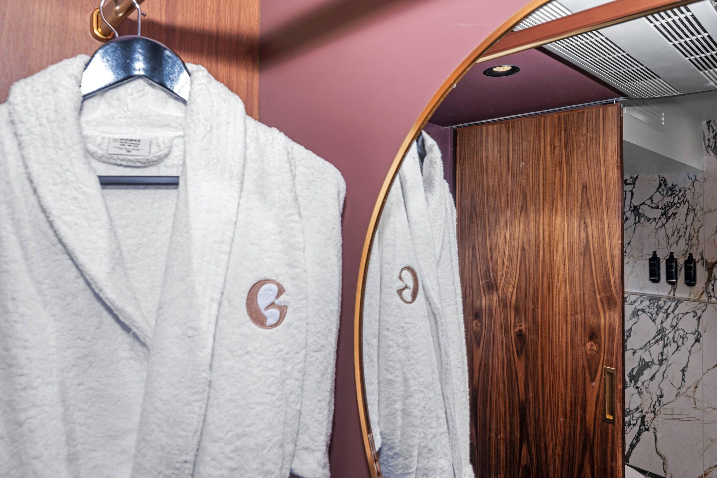 A bathroom with a wooden door, a mirror, and a towel rack with two towels.