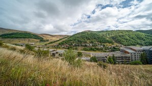 A town nestled in a valley with a mix of residential and commercial buildings, surrounded by forested hills. - Charming Apart for 6 near the Ski Slopes (Allos)