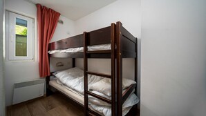 A bunk bed in a small room with a window, a radiator, and a curtain. - Charming Apart for 6 near the Ski Slopes (Allos)