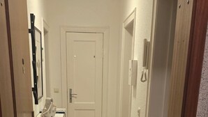 A narrow hallway with wooden flooring leading to a white door at the end. - Beautiful vacation apartment in Timmendorfer Strand (Timmendorfer Strand)