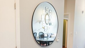 Ein Flur mit einem runden Spiegel an der Wand, einer Bank und einer Tür.