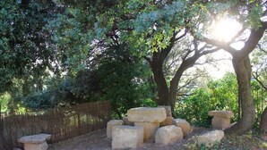 Un entorno natural con un sendero de tierra, estructuras de piedra y una cerca de madera.