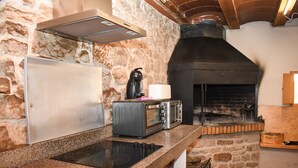 Una cocina con pared de piedra, horno empotrado, microondas, tostadora y campana extractora de acero inoxidable.