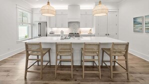 A modern kitchen with white cabinetry, a large island with bar stools, and pendant lighting. - Steps to Seacrest! Private Pool, Bikes, 4 KING Bedrooms! Beach Tram! (Santa Rosa Beach)