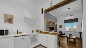 A modern kitchen with white cabinetry, a built-in oven, and a wooden countertop. - Muranów Apt - 49m2, City View - By Rentujemy (Warszawa)