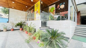 Un restaurant avec un plafond en bois et des plantes en pot devant l’entrée.