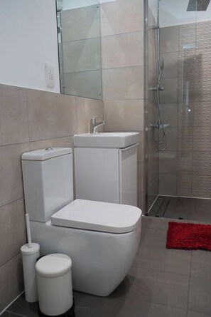 A modern bathroom with a toilet, bidet, and shower. - Loxwood House (Accra)