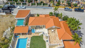 A residential property with a swimming pool, a patio with outdoor furniture, and a well-maintained lawn. - Rooi Koochi 29-b (Savaneta)