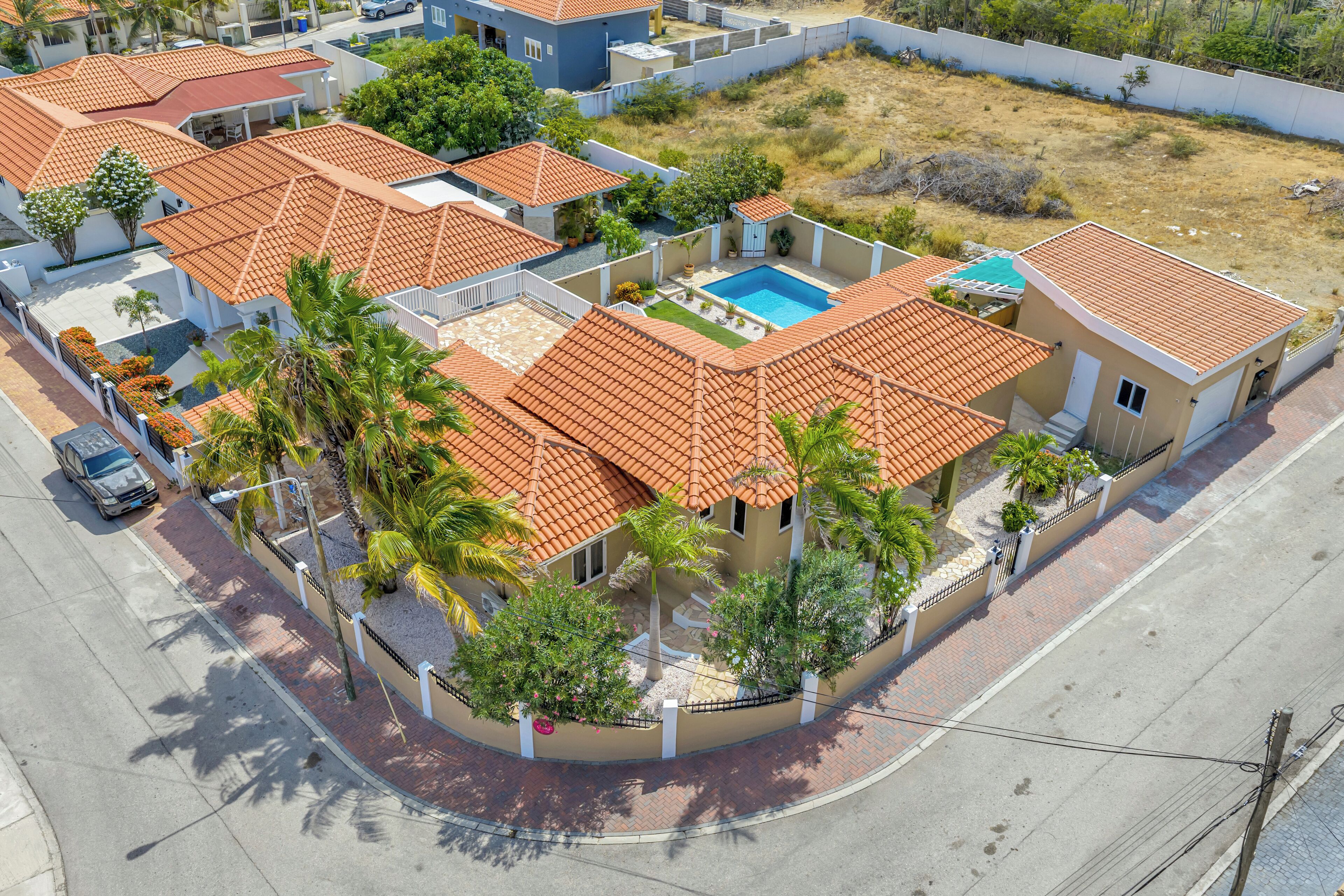 Zona residencial amb cases de teulades vermelles, piscina i palmeres.