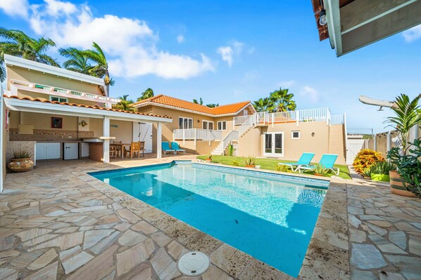 A two-story house with a swimming pool, outdoor seating, and a staircase leading to a balcony. - Rooi Koochi 29-b (Savaneta)