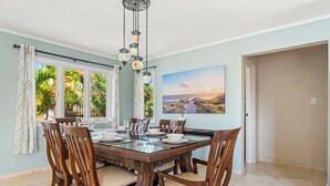 A dining area with a large wooden table, chairs, and hanging decorative lights. - Rooi Koochi 29-b (Savaneta)