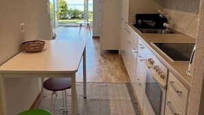 Eine kleine Küche mit Blick ins Freie, ein Essbereich und ein Stuhl.