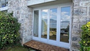 Ein Steinhaus mit einer großen Glasdoor und einem kleinen Holzdeck.