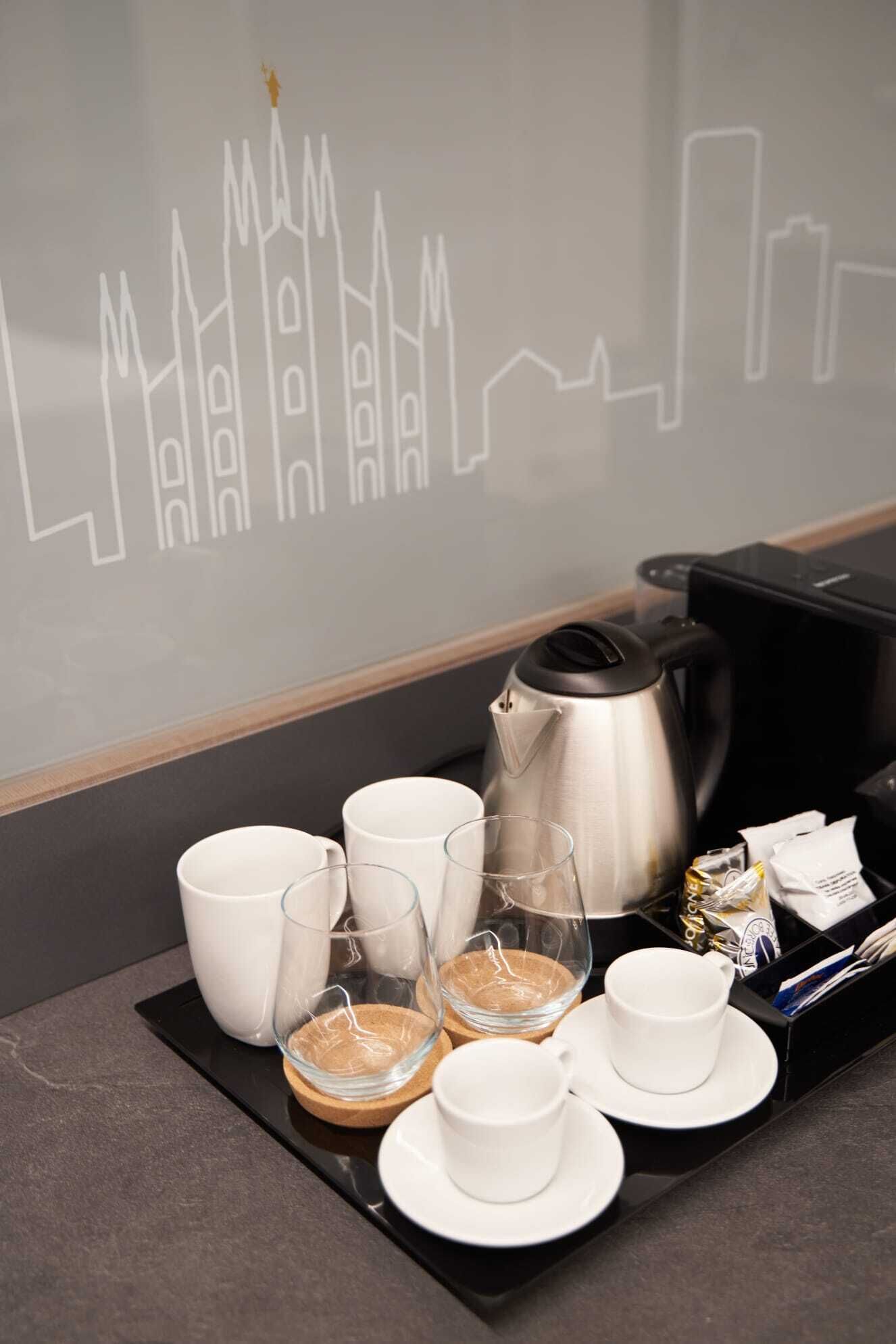 Ein ordentlich gedeckter Frühstückstisch mit Kaffeemaschine, Tassen, Gläsern und einer Platte mit Speisen.
