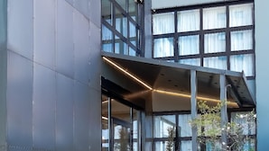 A modern building with a covered entrance, large windows, and a landscaped area with plants. - CA' SAN CRISTOFORO (Milan)