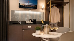 A compact kitchen with a TV, a city skyline poster, a bottle of champagne, and glasses on a table. - CA' SAN CRISTOFORO (Milan)