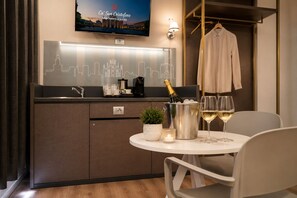 Una cocina compacta con televisión, un cartel con vistas a la ciudad, una botella de champán y copas sobre una mesa.