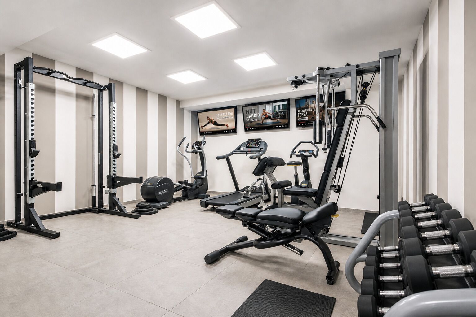 Un gimnasio con diferentes equipos de ejercicio, incluyendo una cinta de correr, máquinas de pesas y mancuernas.