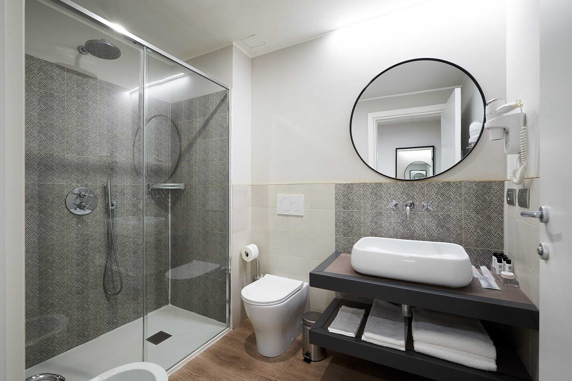 Une salle de bain moderne dotée d’une douche à parois de verre, de toilettes et d’un meuble-lavabo avec un évier et un miroir.