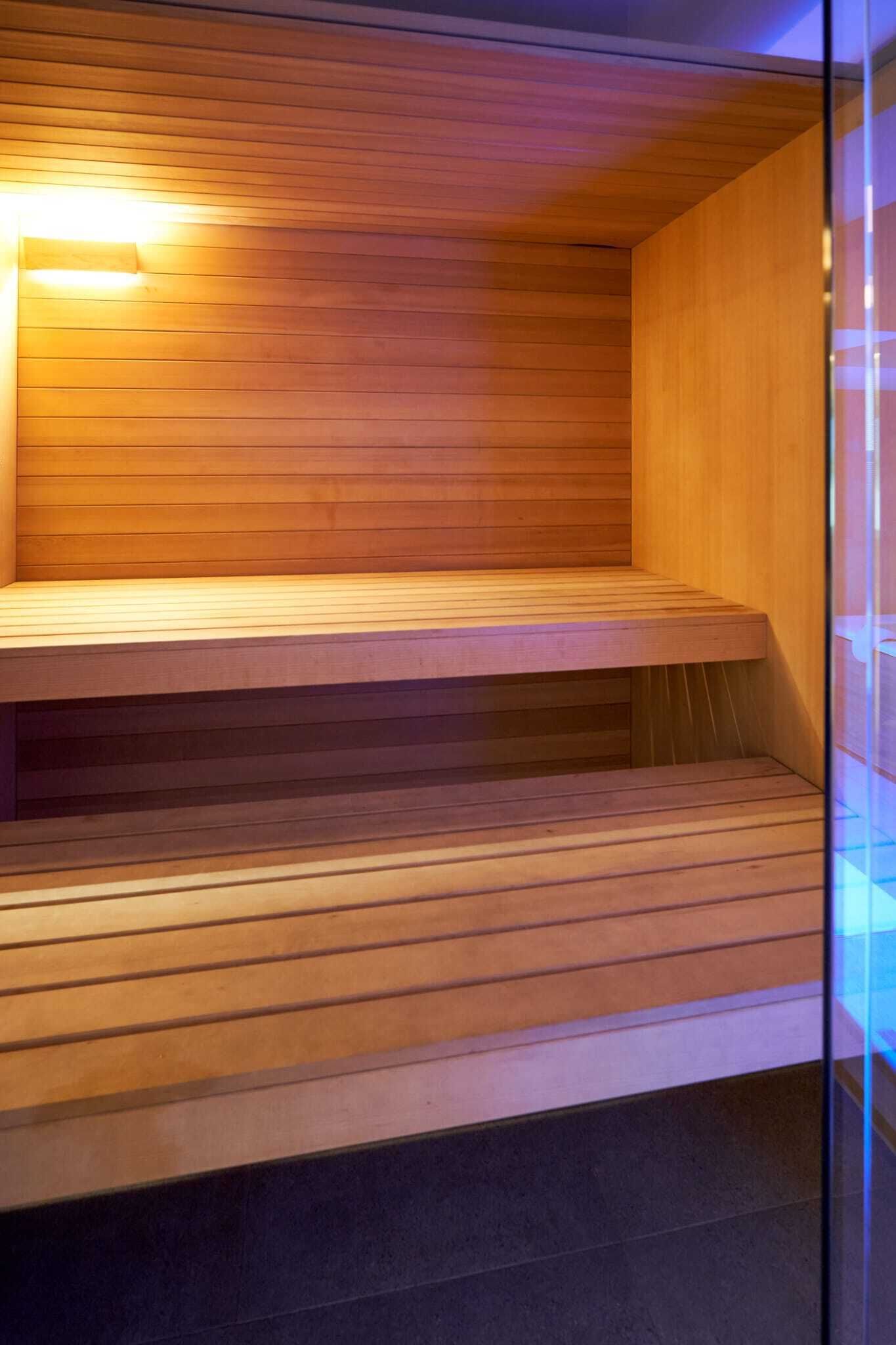 Een sauna met houten banken en een glazen scheiding.