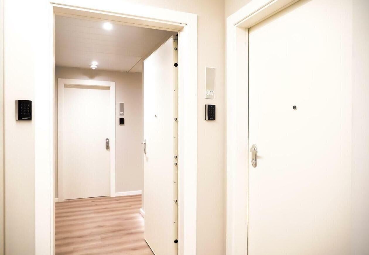 Ein Hotelkorridor mit Holzboden, einer Tür mit Nummernschild und einem Zahlenschloss.