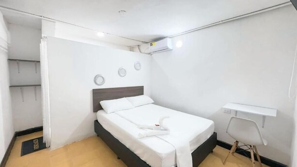 A hotel room with a bed, a desk, and a chair.
