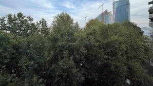 A view of a cityscape with a modern glass building under construction, surrounded by dense green trees. - Apartment 2 minutes from Mico/FieraMilano and Citylife (MM5) (Milano)