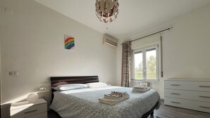 A bedroom with a bed, bedside tables, a dresser, a window with curtains, and a ceiling light fixture. - Apartment 2 minutes from Mico/FieraMilano and Citylife (MM5) (Milano)