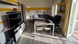 A compact living space with a sofa, a dining table with chairs, a TV, and a small kitchen area. - Apartment 2 minutes from Mico/FieraMilano and Citylife (MM5) (Milano)